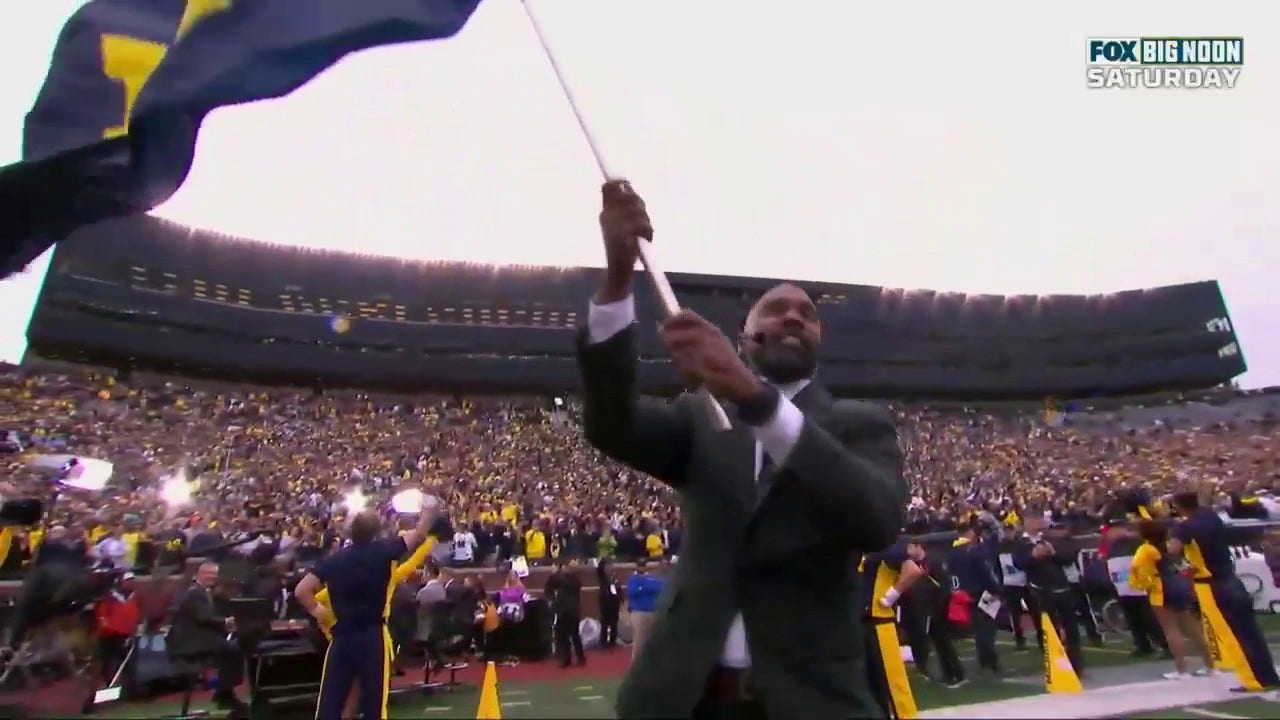Former Heisman trophy winner Charles Woodson waves the Michigan flag, leading the Wolverines out of the tunnel