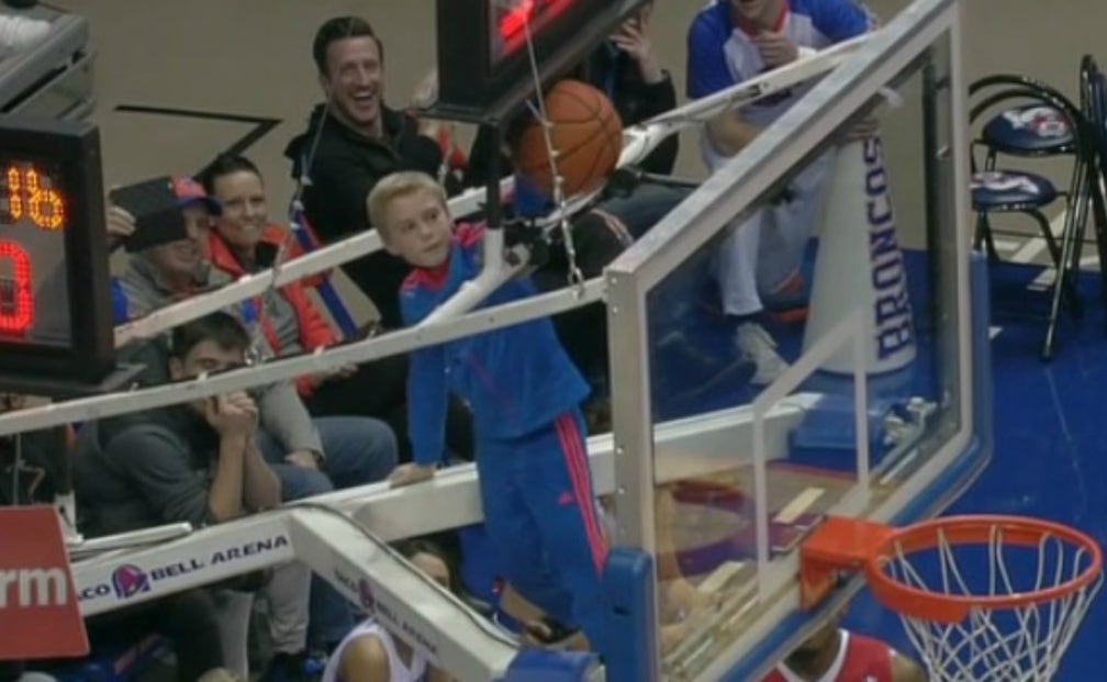 Watch a brave young fan climb above the rim to free basketball stuck