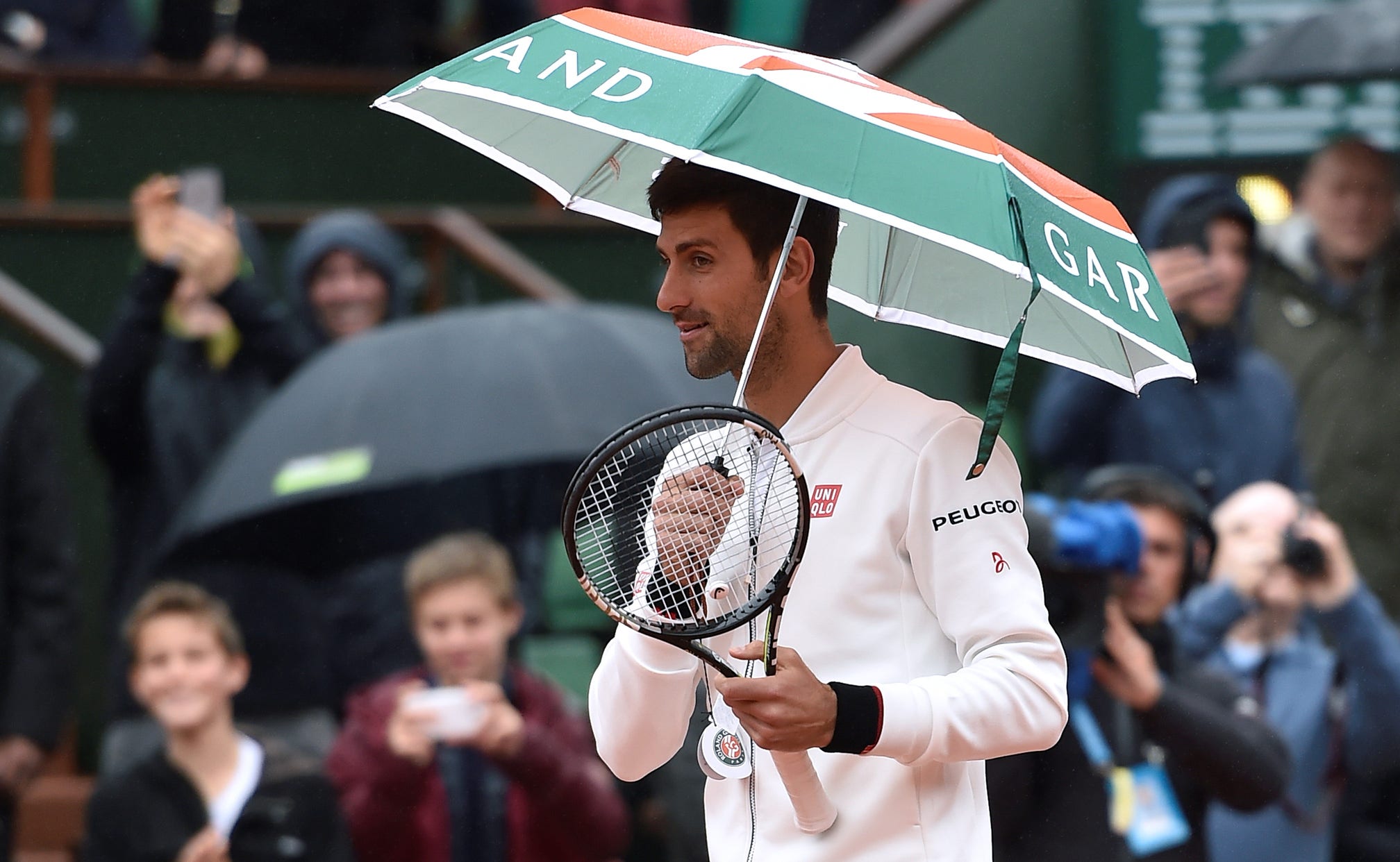 Novak Djokovic borrows an old woman's umbrella and takes a stroll at