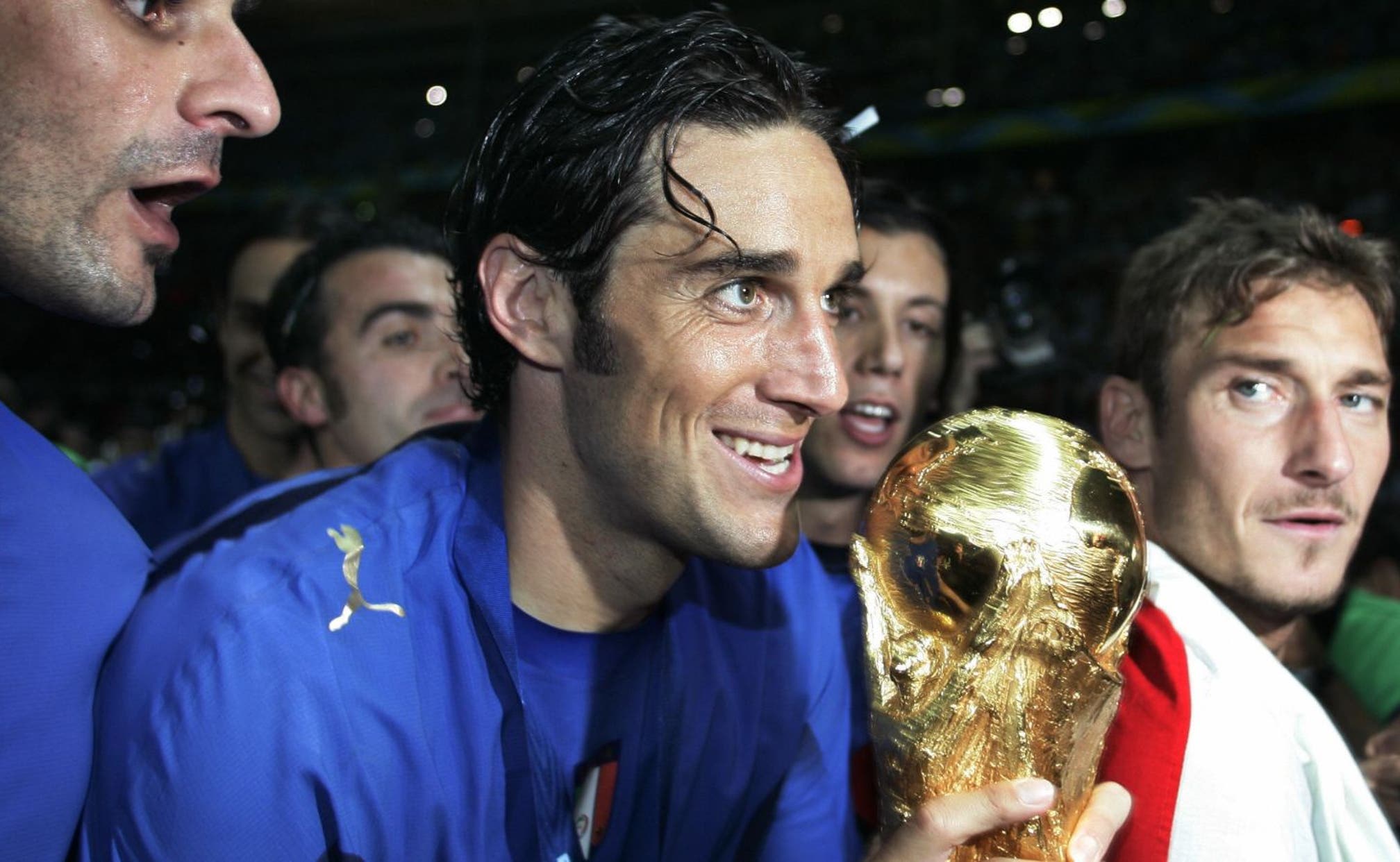  Luca Toni celebrates scoring a goal for Italy in the 2006 World Cup, surrounded by his teammates.