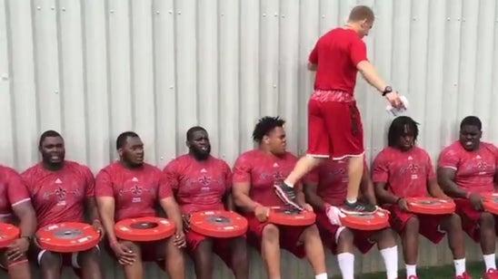 College football coach walks over his team in creative workout
