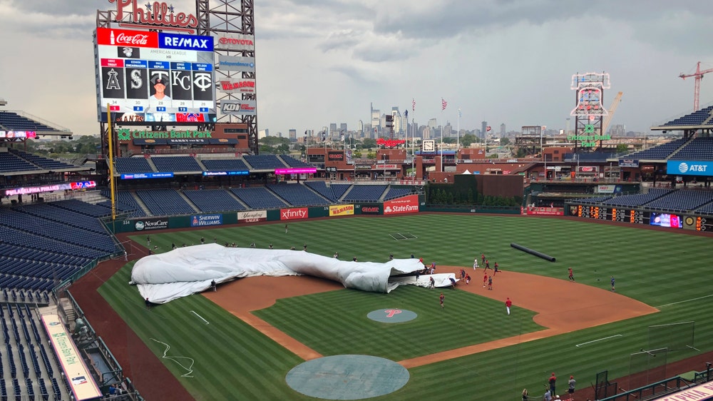 Giants, Phillies players help corral wind-blown tarp