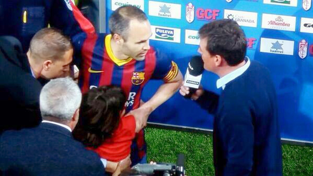 Young pitch invader clings to Iniesta during his interview