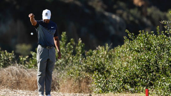 The Latest: A clutch birdie by Woods allows him to make cut