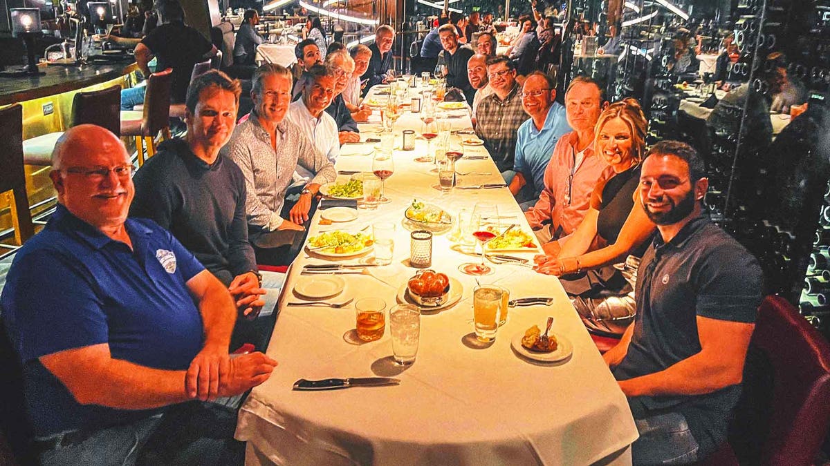 Saturday night dinners are great for team building, where a statistician from South Dakota like Jeff Nelson (left, in blue shirt), can sit and chat with a seven-time Super Bowl champ. (Photo by Richie Zyontz)