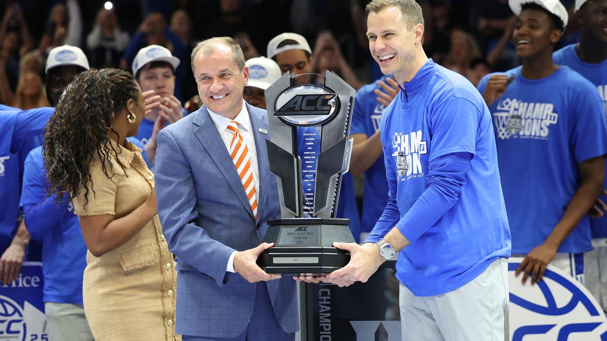 ACC Commissioner Jim Phillips presents Duke coach Jon Scheyer with the trophy during the ACC Men's basketball tournament championship game. (Photo by John Byrum/Icon Sportswire via Getty Images)