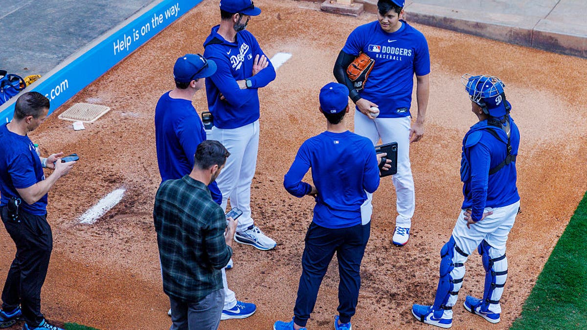 Los Angeles Dodgers Shohei Ohtani (17) chats with coaches after pitching a bullpen session. Ohtani increased his limit during his last session in San Diego as he threw three simulated innings. (Gina Ferazzi / Los Angeles Times via Getty Images)
