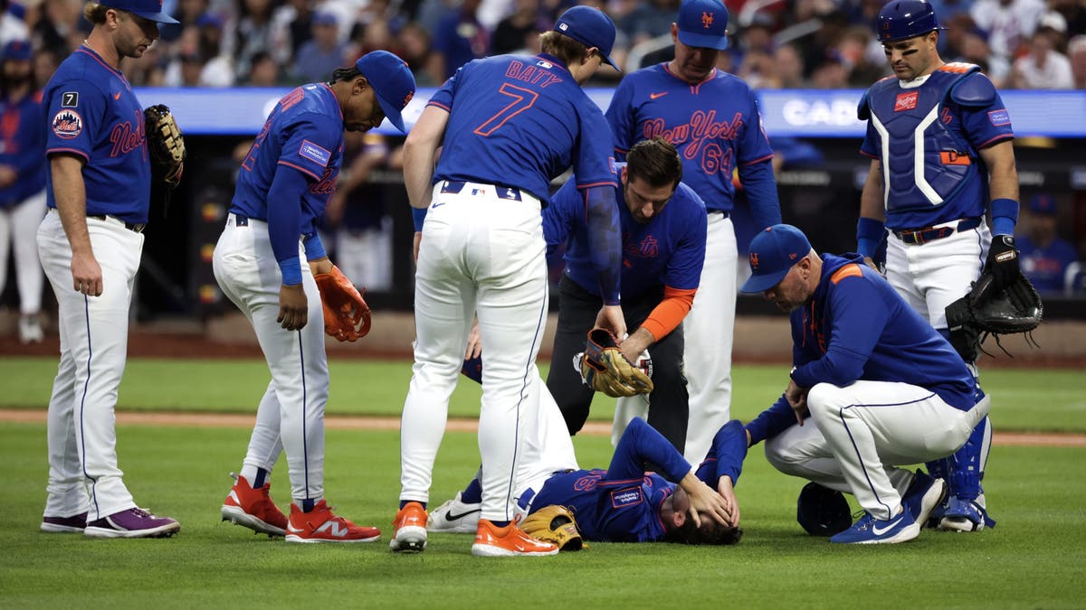 Mets teammates comfort Griffin Canning as his hands cover his face. (Photo by Kent J. Edwards/Getty Images)
