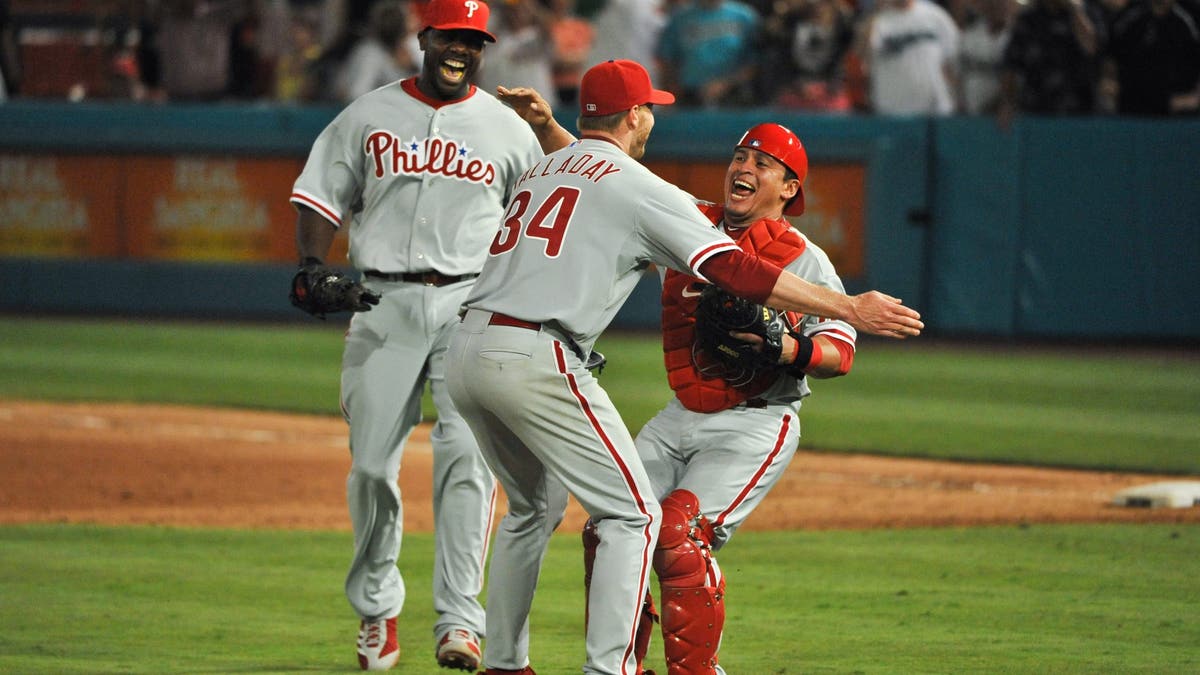 Roy Halladay shared an embrace with his Phillies teammates following his perfect game in 2010. (Photo by Ronald C. Modra/Getty Images)