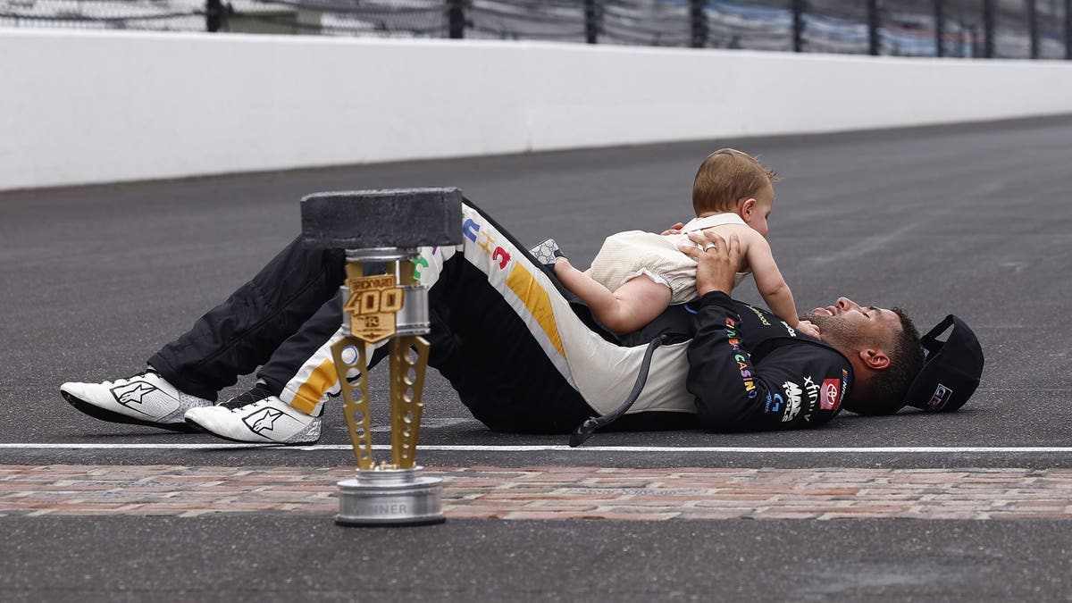 An exhausted Bubba Wallace celebrates with his son Becks after winning the Brickyard 400