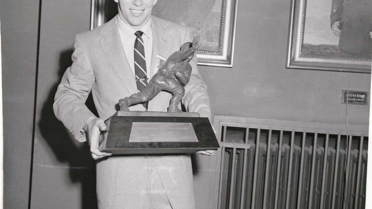 Johnny Lattner, Notre Dame's two-time All-American halfback, proudly displays the Heisman Trophy.