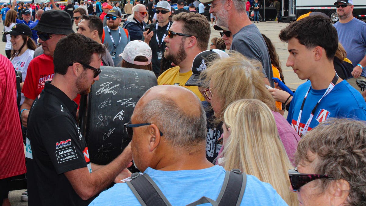 Back at the garage, there are more autographs. Fans bring everything you can think of to sign, including photos, trading cards, jerseys, diecast model cars<strong> </strong>and, yes, even tires. (Photo by Ed McGregor/FOX Sports)