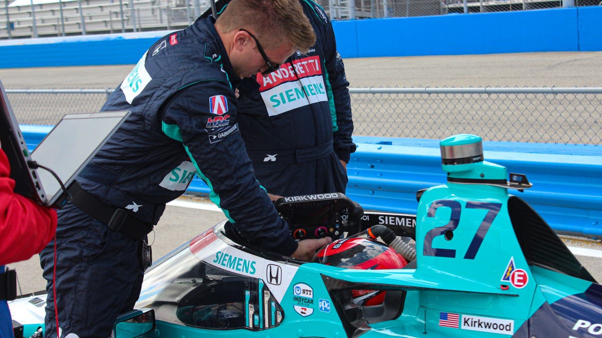 The team affixes Kirkwood's steering wheel into the cockpit. The high-tech device doesn't just steer. It features a series of buttons and paddles for critical functions and also provides real-time data for drivers. (Photo by Ed McGregor/FOX Sports)