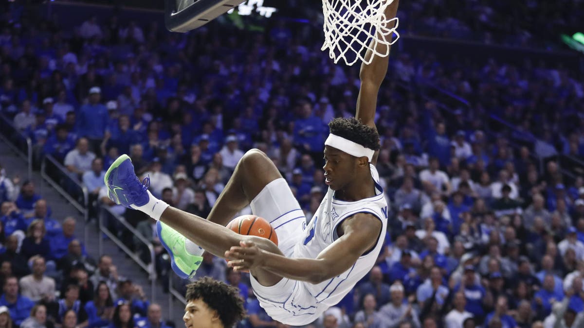 AJ Dybantsa #3 of the Brigham Young Cougars swings from the rim after dunking against the Arizona Wildcats. (Photo by Chris Gardner/Getty Images)