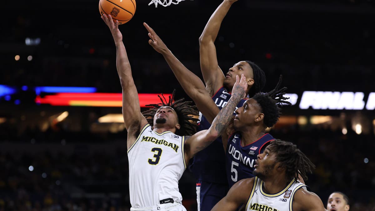 Elliot Cadeau of the Michigan Wolverines shoots the ball against Tarris Reed Jr. of the UConn Huskies. (Photo by Patrick Smith/Getty Images)