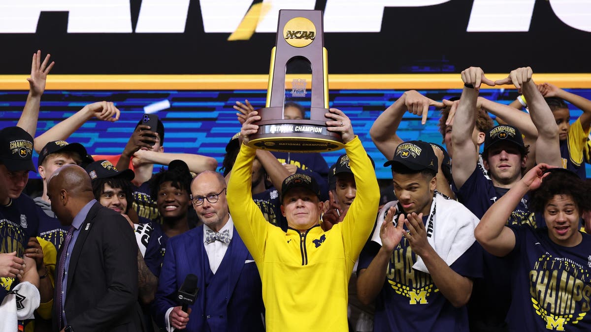 Michigan head coach Dusty May hoists the trophy after defeating the UConn Huskies in the national championship. (Photo by Michael Reaves/Getty Images)