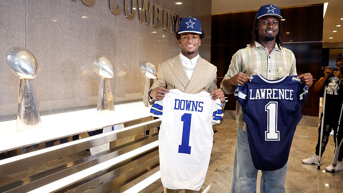Newly drafted Dallas Cowboys defensive player Caleb Downs (left) and Malachi Lawrence pose with their first-round jerseys following their introductory press conferences at The Star in Frisco, April 24, 2026. The Cowboys 5 Super Bowl trophies are pictured as well. (Tom Fox/The Dallas Morning News via Getty Images)