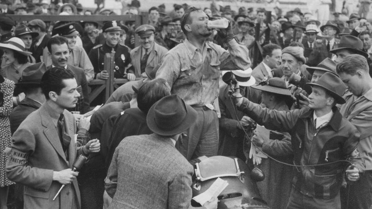 1940 Indy 500 race car winner Wilbur Shaw is seen drinking milk during the traditional Brickyard ceremony.